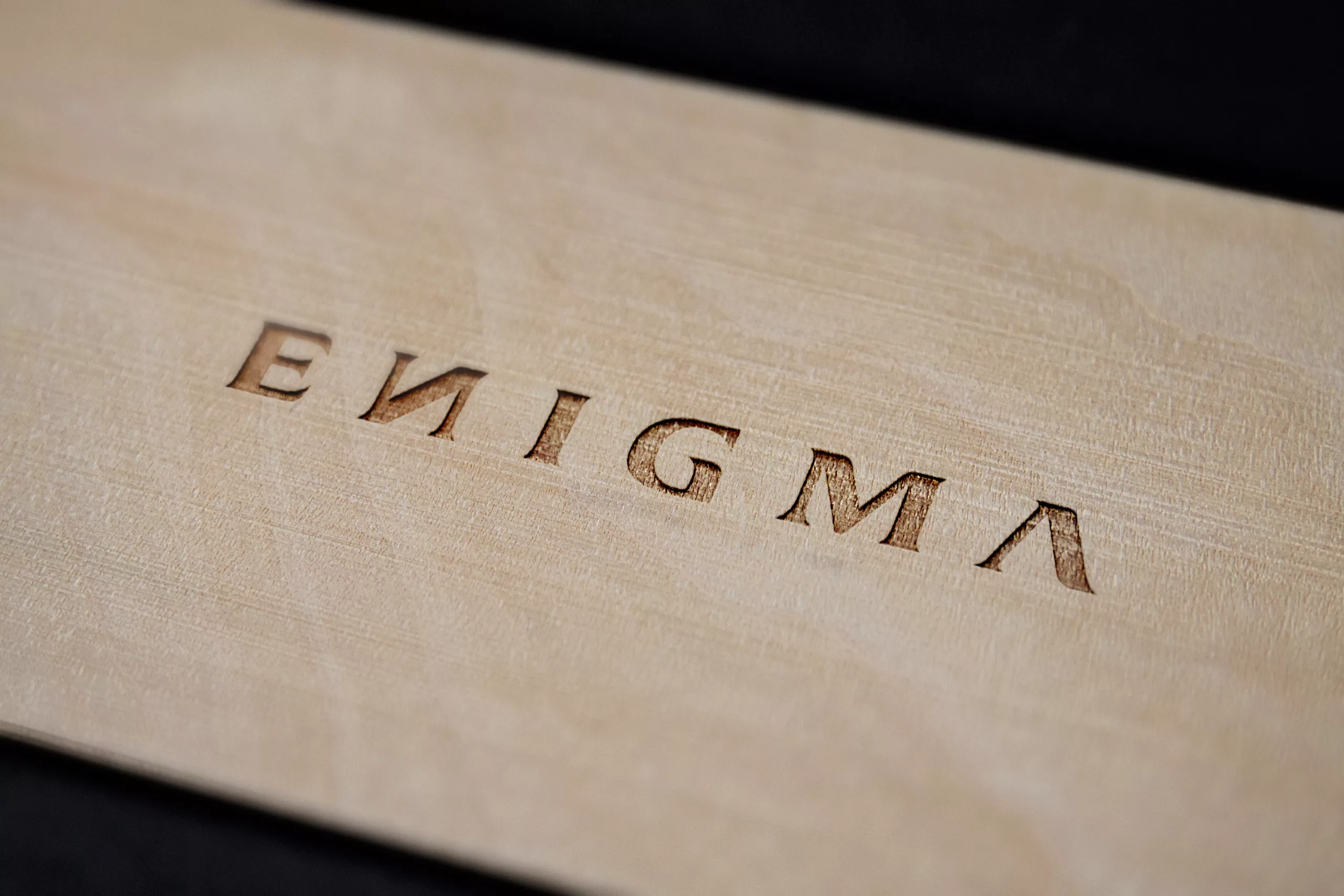 Logo ENIGMA gravé dans une plaque en bois clair